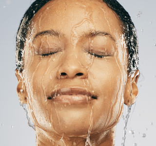 Woman's face with water running down it